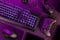 Purple lit keyboard amidst wireless devices