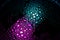 Purple, magenta, teal and cyan droplets illuminated with colored bulb with dark background