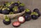 Purple mangosteens in a rattan basket on burlap background