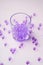 Purple marbles in drinking transparent glass with scattered marbles on white background