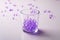 Purple marbles in drinking transparent glass with scattered marbles on white background