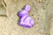 Purple mold from a beach set of toys in the form of a hare lies on the sand