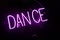 Purple neon light creating the word `DANCE` on a black wall