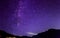 Purple night sky stars. Milky way across mountains