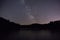 Purple night sky stars over mountain lake. Milky way galaxy in summer starry night