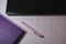 purple notepad, black laptop and pink pen