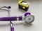 Purple phonendoscope and portable pulse oximeter on white background