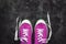 purple-pink-lilac sneakers with untied laces on a dark concrete background. Copy space. View from above