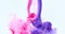 Purple and pink paints splash curves in water on white. Acrylic paint drop background
