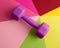 Purple plastic dumbbell for sports on color background