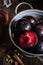 Purple plums in gray colander on dark wooden background