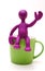 Purple puppet of plasticine sitting on cup