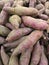 Purple, raw sweet potatoes, stacked up in a market bin, ready for their eager buyers.