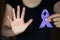 Purple ribbon in a woman`s hand, Domestic Violence Awareness Month October concept with deep purple awareness ribbon