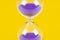 Purple sand clock hourglass on yellow background