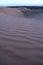 Purple sand dunes in the desert at nightfall.