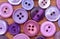 Purple sewing buttons from above on a wood table