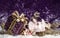 Purple shiny gift with a gold bow, on a snowy background