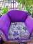 a purple single sofa chair that is worn and damaged with age