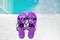 Purple slippers near swimming pool at poolside. Summer vacation. Lilac sandals by swimming pool. Blue sea surface with waves, text