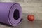 Purple sports mat for sports on the background of a red apple, front view. Sport is good for your health.