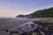 Purple sunrise in tropical beach, waves and stones on shore