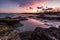 Purple sunset over a tropical rocky beach