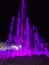 Purple water fountain and multi-colored lighted icicle walls in ice castle