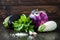 Purple and white eggplant (aubergine) with basil and garlic on dark wooden table. Fresh raw farm vegetables - harvest fr