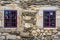 Purple window on medieval castle made of stone and rocks.