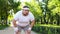 Purposeful fat man running in park, out of breath, persistent motivation