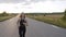 Purposeful, young sporty girl with long hair jogging on road at evening nature