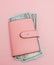 Purse with one hundred dollars banknotes on pink background. Flat lay, top view