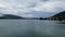 Push in shot through trees towards lake Tegernsee with marina, church and mountain panorama in Bavaria, Germany