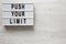 `Push your limit` words on a modern board on a white wooden background, top view. Overhead, from above, flat lay. Space for text