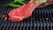 Put t bone beef steak on the grill grate over, flame. Close up. Slow motion