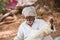 PUTTAPARTHI, ANDHRA PRADESH, INDIA - JULY 9, 2017: Rustic old man in a traditional white dress with a fishing net. Close-up.