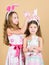 Putting bunny ears on. Cute children in Easter bunny style holding hearts. Happy children celebrating Easter. Small