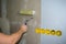 Putting glue roller. Men`s hand holds instrument. Wallpaper wall with sockets.