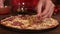 Putting salami slices on pizza - closeup