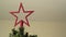 Putting a star shaped ornament on top of a christmas tree
