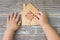 A puzzle house in the hands of a child on a wooden background.