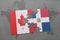 puzzle with the national flag of canada and dominican republic on a world map background.