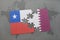 puzzle with the national flag of chile and qatar on a world map background.