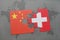 puzzle with the national flag of china and switzerland on a world map background.