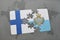 puzzle with the national flag of finland and san marino on a world map background.