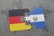 puzzle with the national flag of germany and el salvador on a world map background.