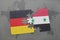 puzzle with the national flag of germany and syria on a world map background.