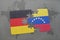 puzzle with the national flag of germany and venezuela on a world map background.