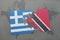 puzzle with the national flag of greece and trinidad and tobago on a world map background.